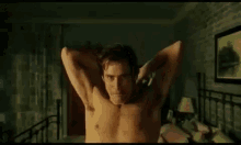 a shirtless man is standing on a bed with his arms outstretched in a bedroom .