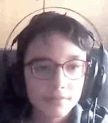 a young boy wearing glasses and headphones is sitting in a chair .