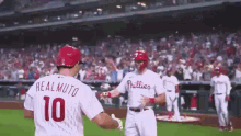 a couple of baseball players are standing on a field . one of the players is wearing a number 10 jersey .