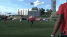 a man in a red shirt is walking on a field with a sign that says ball park in the background