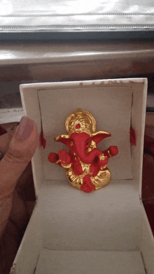 a gold and red statue of ganesha in a box