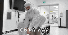 a man in a white suit is kneeling down in a room with the words `` on my way '' .