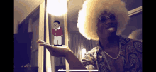 a man with an afro and sunglasses is holding a pixelated figure