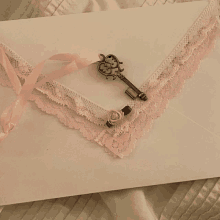 a white envelope with pink lace and a key on top