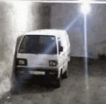 a white van is parked against a wall in a garage .