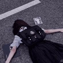 a girl laying on the ground with a book and a backpack that has the letter v on it