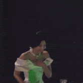 a woman in a white dress and pearl necklace is holding a green object .