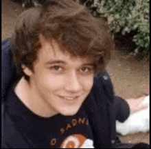 a young man wearing a t-shirt is smiling for the camera .