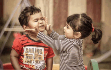 a little girl putting her hand on a little boy 's face .