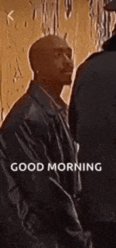 a man in a leather jacket is standing next to a man in a suit and says `` good morning '' .