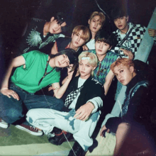 a group of young men are posing for a picture and one of them is wearing a green shirt with the letter g on it