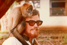 a man with a monkey on his head wearing glasses