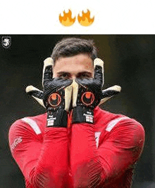 a soccer goalie is making a face with his gloves .