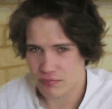 a close up of a young man 's face with a white shirt on .