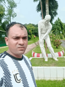 a man wearing a juventus shirt stands in front of a statue of a golfer