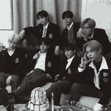 a group of young men sitting on a couch with a cake on the table