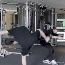 two men are doing exercises in a gym with a sign that says ' e ' on it