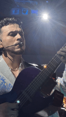 a man playing a guitar with a microphone in his ear