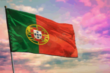 the portuguese flag is waving in the wind against a cloudy sky