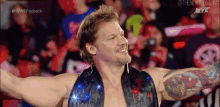 a wrestler with his arms outstretched in front of a crowd .