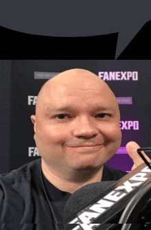 a bald man stands in front of a fanexpo banner