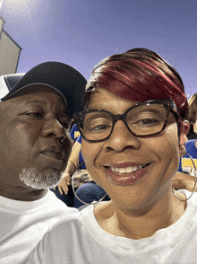 a man and a woman are posing for a picture and the woman is wearing a white shirt that says ' a '