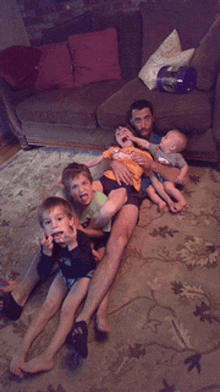 a man is laying on the floor with four children including a baby