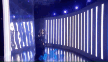 a woman is standing in front of a wall of lights in a room .