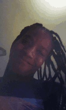 a woman with dreadlocks is smiling and wearing a black shirt