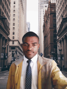 a man wearing a yellow jacket and tie is standing in front of a city