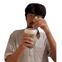 a man wearing glasses is drinking from a cup