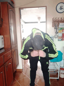 a man in a black and green adidas tracksuit stands in front of a knorr box