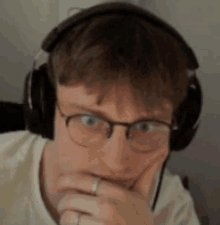 a man wearing headphones and glasses is making a face .