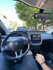 a man is driving a peugeot car with a rear view mirror visible