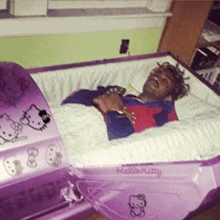 a person is laying in a pink hello kitty coffin .