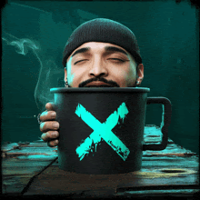 a man with his eyes closed is holding a black mug with a blue x on it