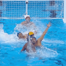 a group of men are playing water polo in a pool and one of them is reaching for the ball