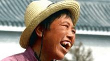 a close up of a person wearing a straw hat laughing .