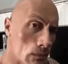 a close up of a bald man 's face looking at the camera .