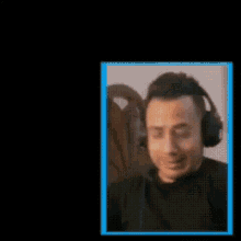 a blurry picture of a man wearing headphones covering his face with his hand .