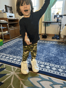 a little boy standing on a rug with his arms outstretched in front of a bottle of clorox