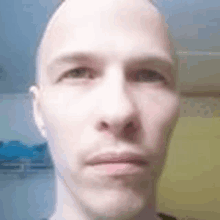 a close up of a man 's face with a shaved head .