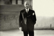 a man in a suit and tie is standing with his hands in his pockets .