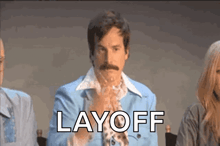 a man in a blue suit and tie is sitting at a table with other people and says layoff .