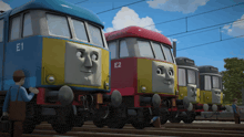 a blue train with e1 on the front is next to a red train with e2 on it