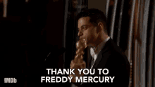 a man in a suit is giving a speech and says thank you to freddy mercury .