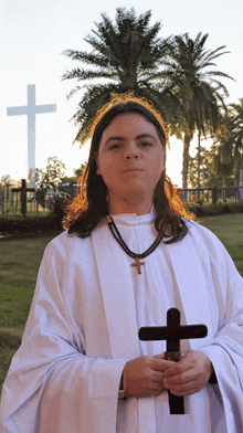 a man in a white robe holding a cross in front of a large cross