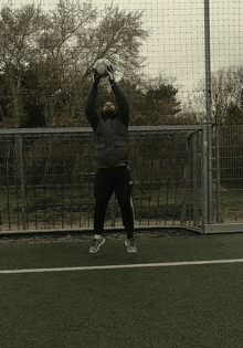 a man holds a soccer ball in his hands while standing on a field