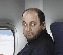 a man with a bald head is sitting on an airplane