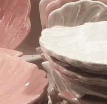 a stack of pink and white seashell shaped plates